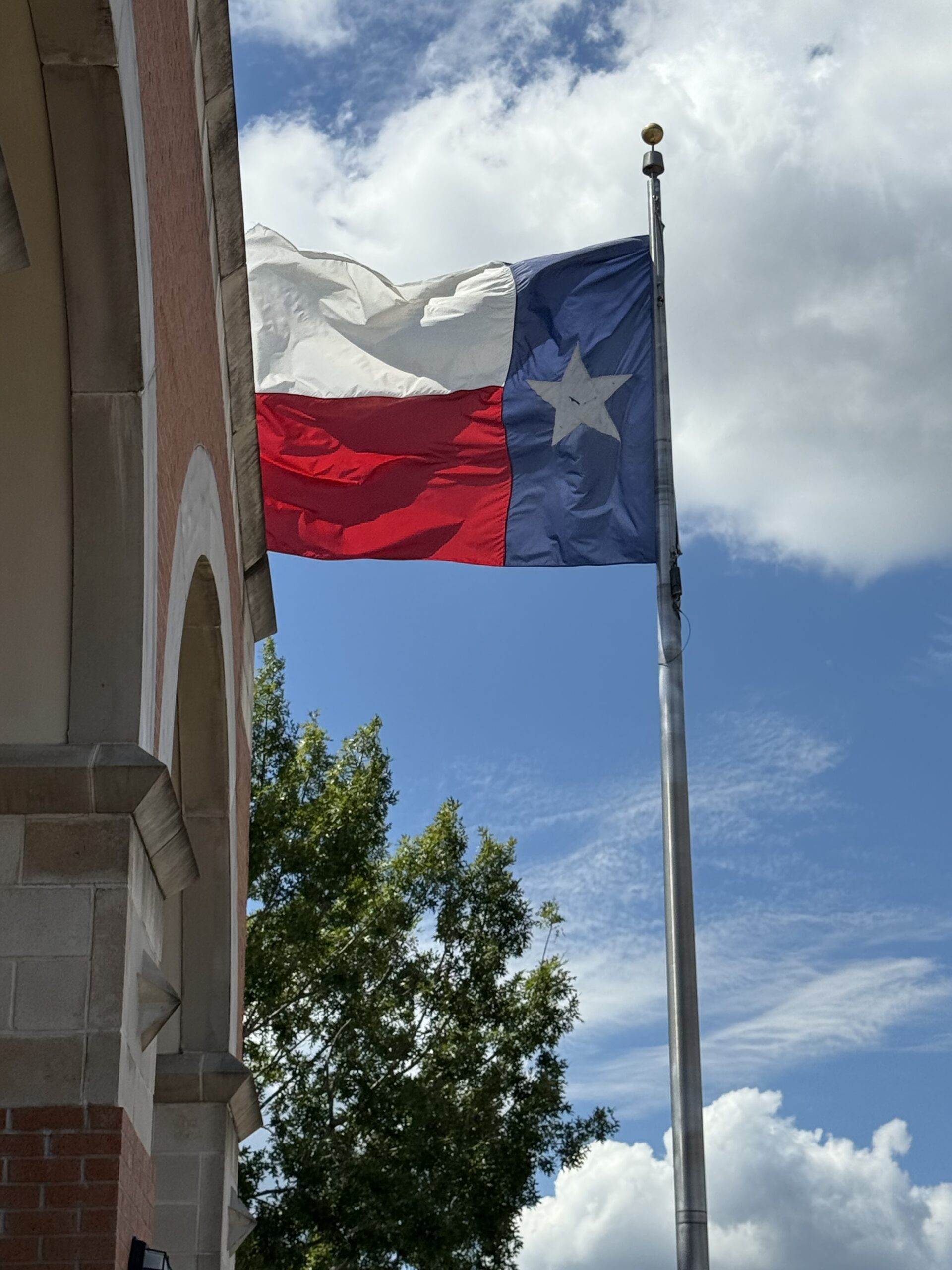 Texas flag flying beside a historic brick building in downtown Conroe, Texas